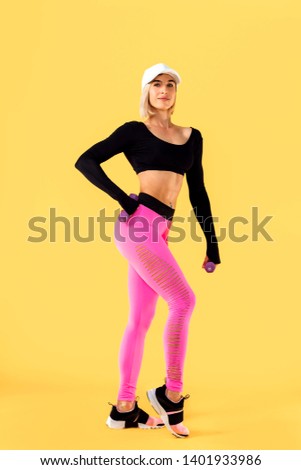 Sporty woman in fashionable sportswear on yellow background. Strength and motivation.