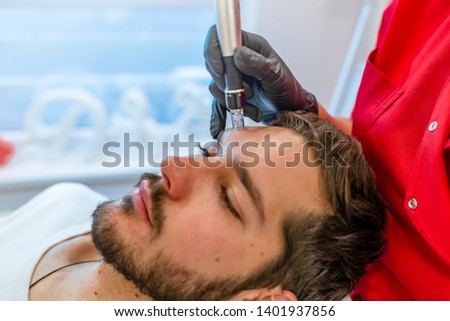 Man at the spa getting a facial dermapen treatment.  Man With Perfect Skin Getting Beauty Treatment Indoors.  Cosmetology.  Skin Lift Procedure.