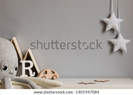 Stylish and cozy childroom with plush octopus, wooden mountain box, car and hanging white stars on the gray wall. Bright and sunny interior. Copy space. Minimalistic childish decor. Template.