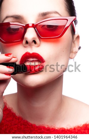 young woman paints her lips with red lipstick
