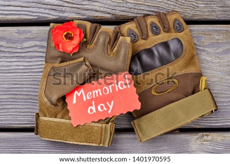 Pair of fingerless gloves and red poppy. Grey wood background.