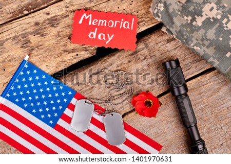 Veteran's accessories on wood. American flag, dog tags, red poppy and torch. Attributes for memorial day.