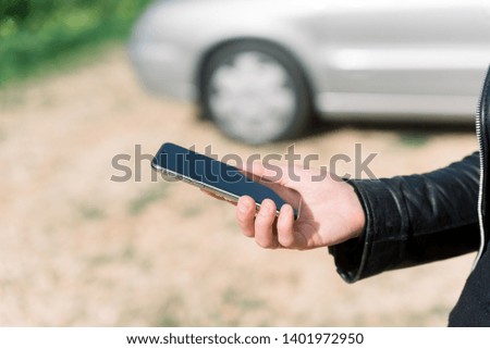Woman using a mobile phone on car background, closeup image of social media, communication technology and busy lifestyle