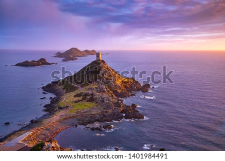 View of Pointe de la Parata on the west coast of Corsica France Europe. A ruined Genoese tower sits on top of the rocky promontory overlooking the archipelago of the Sanguinaires on the colored sunset Royalty-Free Stock Photo #1401984491