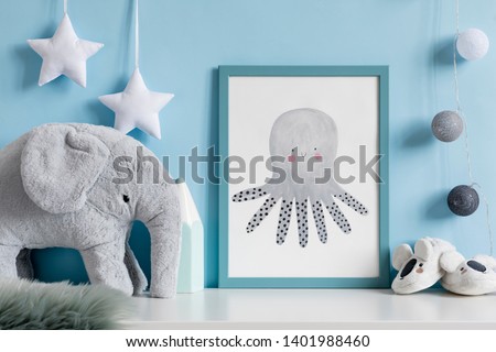 Cozy scandinavian newborn baby room with mock up poster frame, plush elephant ,koala slippers and children accessories. Stylish interior with blue walls and haniging cotton balls and stars. Template.
