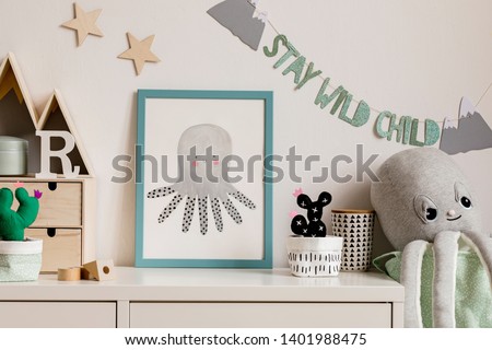 Cozy scandinavian nursery interior with mock up photo frame, plush octopus, cacti and wooden accessories. Hanging stylish inscription and stars on the white background wall. Template. Real photo.