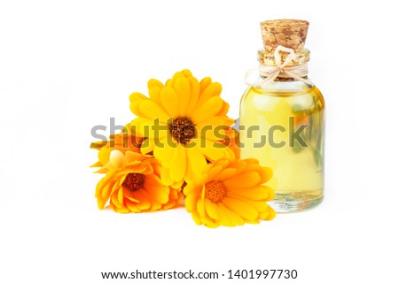 Glass bottle of calendula essential oil with fresh marigold flowers isolated on white background. Aromatherapy marigold oil herbal medicine background concept with copy space