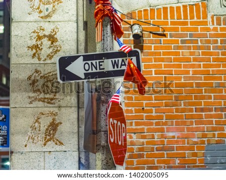 Chinese and US flags on a traffic pole with one way and stop sign