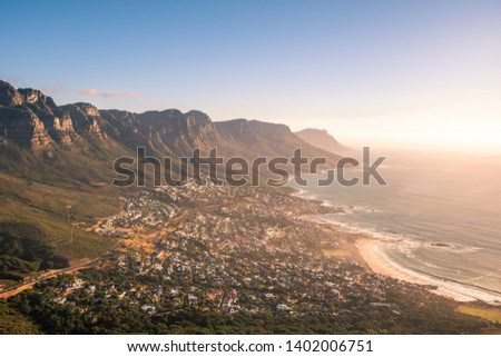 Landscape photo of a sunset over Camps Bay with the sun setting on the right and The Twelve Apostles on the left. Shot froim Lion's Head in the city of Cape Town, Western Cape, South Africa.