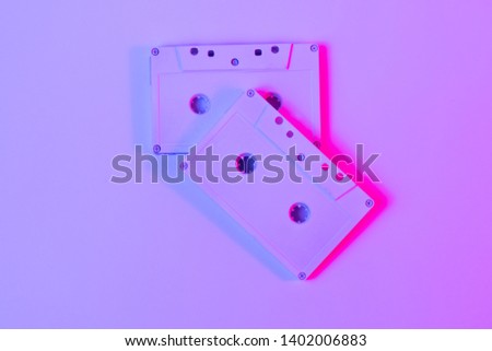 Trendy reviving retro audio cassette tape on pink and green neon light. Analogue music hipster trend. Bright neon colors. Minimal and surreal. style of the 80's Top view