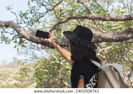 Close up travel woman using smart phone take a photo at tree nature background.Travel,technology,holiday concept.