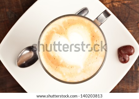 A white table in a cozy cafe with a cup of coffee and milk, love is above in the air.
