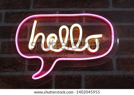 Neon sign background saying " HELLO " Sign hanging on a wall and lit brightly.