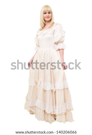 Beautiful Victorian Lady standing in sideway in white background. Beige Dress with flowers, Ruffles and Lace. Long fair straight Hair. Looking at the Camera.