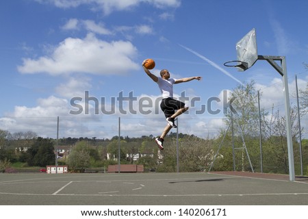 Portrait of a Basketball player in mid air about to Slam Dunk Royalty-Free Stock Photo #140206171