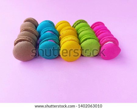 Delicious macaron sweets arranged in rows, colorful macaroon on pink background