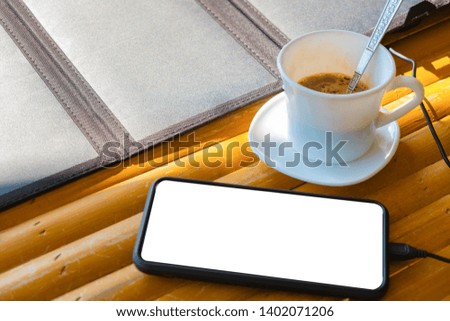 Mobile phone call Placed on a bamboo table in the morning with a coffee cup and saucer With solar cells to power mobile phones