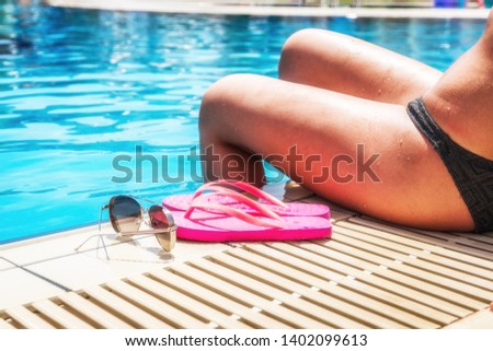 Girl sitting near swimming pool in summer sunny day