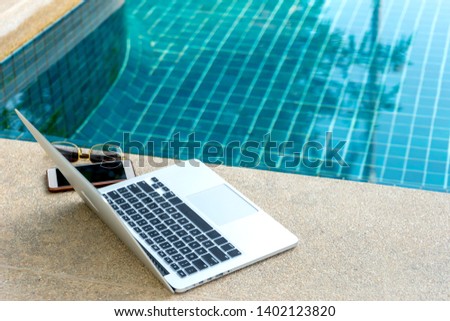 Laptop and smartphone near the swimming pool, modern businessman can work anywhere.