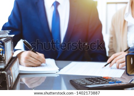 Bookkeeper or financial inspector and secretary making report, calculating or checking balance. Internal Revenue Service inspector checking financial document. Business, tax and audit concepts
