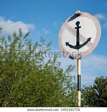 Closeup of a special sign for ships on the background of trees. Parking in this place is prohibited. Crossed anchor in a circle.