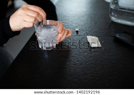 Woman dissolves medicine with soluble sachet in a water. Soluble powder drug dissolved in water, self-medication  without a prescription for headache, toothache and pain. Pain medication