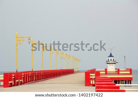 The red bridge extends into the sea with a lighthouse on the bridge.