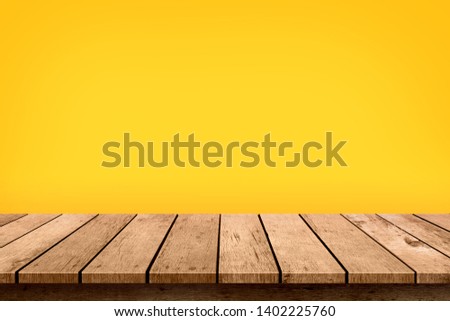 Empty wooden table top on pastel yellow colour background. Used for display or montage your products.