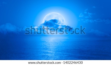 Night sky with full moon in the clouds on the foreground blue sea "Elements of this image furnished by NASA