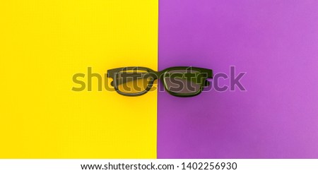 Black 3D glasses, on fun vivid purple yellow background. Flat lay.