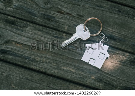 House key with home keyring in on old wood background, copy space