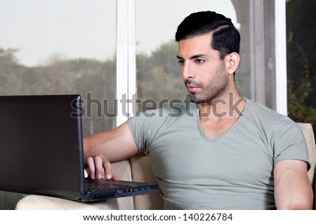happy confident man using laptop and sitting on the sofa