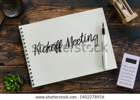 Top view of magnifying glass,plant,pen,calculator,sand clock and notebook written with Kickoff Meeting. Royalty-Free Stock Photo #1402278956