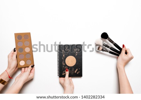 Young woman holding brush with color paint on white background, closeup