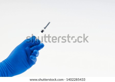 Hand in a blue glove holding syringe isolated on white