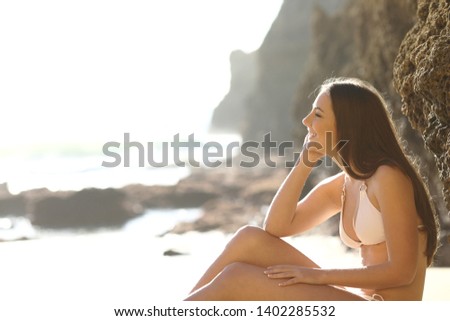 Profile of a pensive tourist in bikini contenplating the beach on summer vacation