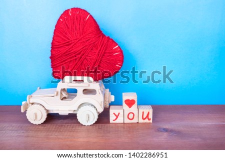 Love concept, red heart and wooden car on the blue background. 