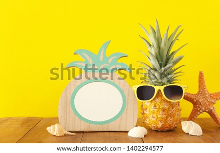 Empty photo frame and funny pineapple with sunglasses. For photography and scrapbook montage