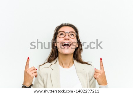 Young european business woman indicates with both fore fingers up showing a blank space.
