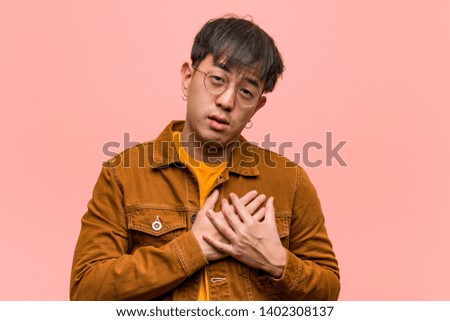 Young chinese man wearing a jacket doing a romantic gesture
