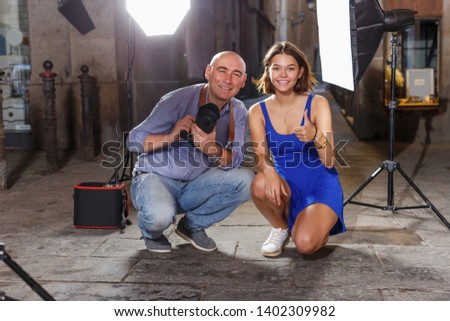 Portrait of smiling girl and professional photographer during photo shoot on old city street
