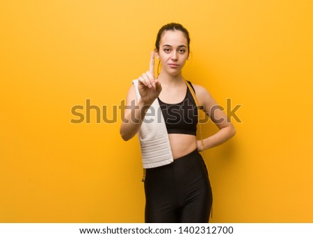 Young fitness girl showing number one