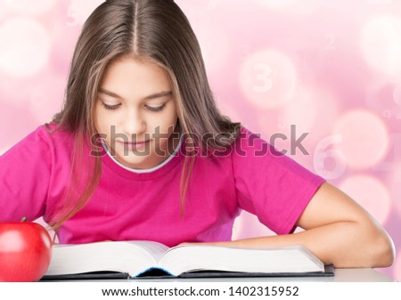 Young school girl reading a book at the library