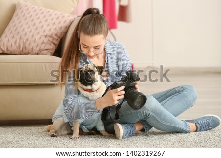 Teenage girl with cute pug dog and photo camera at home