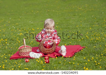 little toddler seated outdoors, in grass with buttercups