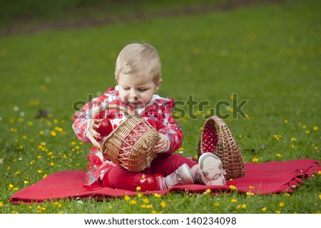 little toddler seated outdoors, in grass with buttercups