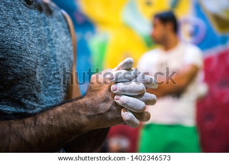 A rock climber hand full of climbing  chalk and climbing wall on the background.