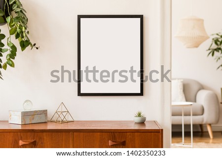 Stylish and retro space of home interior with black mock up frame, design sofa, furnitures, vintage cupboard with elegant accessories, plants and coffe table. Cozy home decor. Minimalistic concept. Royalty-Free Stock Photo #1402350233