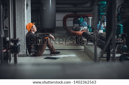 tired energy engineer sitting on the floor at work Royalty-Free Stock Photo #1402362563