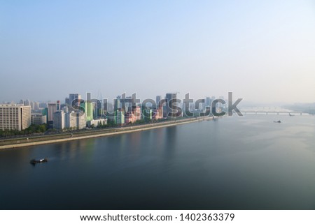 Pyongyang, DPR Korea North Korea and Taedong River in the morning fog. View facing upstream, modern residential complex and Ryugyong Hotel. View from Yanggakdo Hotel  Royalty-Free Stock Photo #1402363379